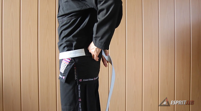 On applique une extrémité de la ceinture dans le dos, sur la hanche avant de faire le tour avec sa ceinture de JJB